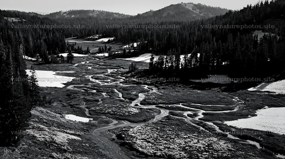 Snowy meadow valley with winding river and forested hills – nature photography 10608x5938