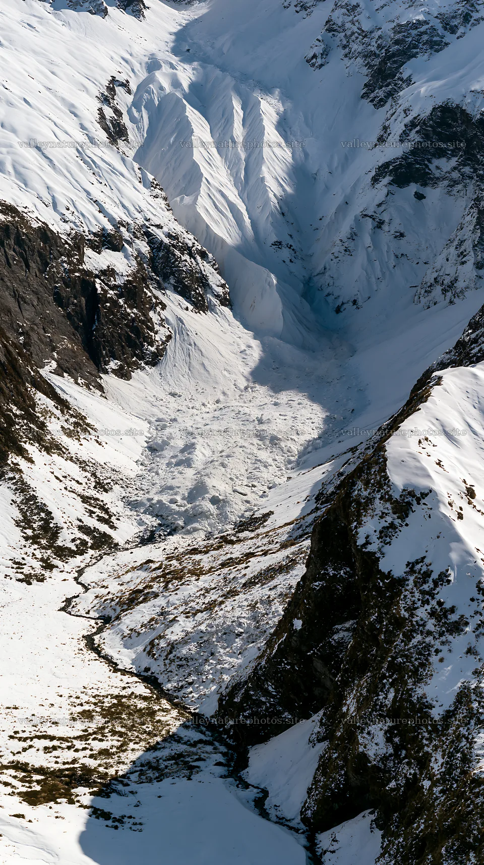 Aerial view of snowy meadow valley surrounded by mountains – nature photography 5938x10608