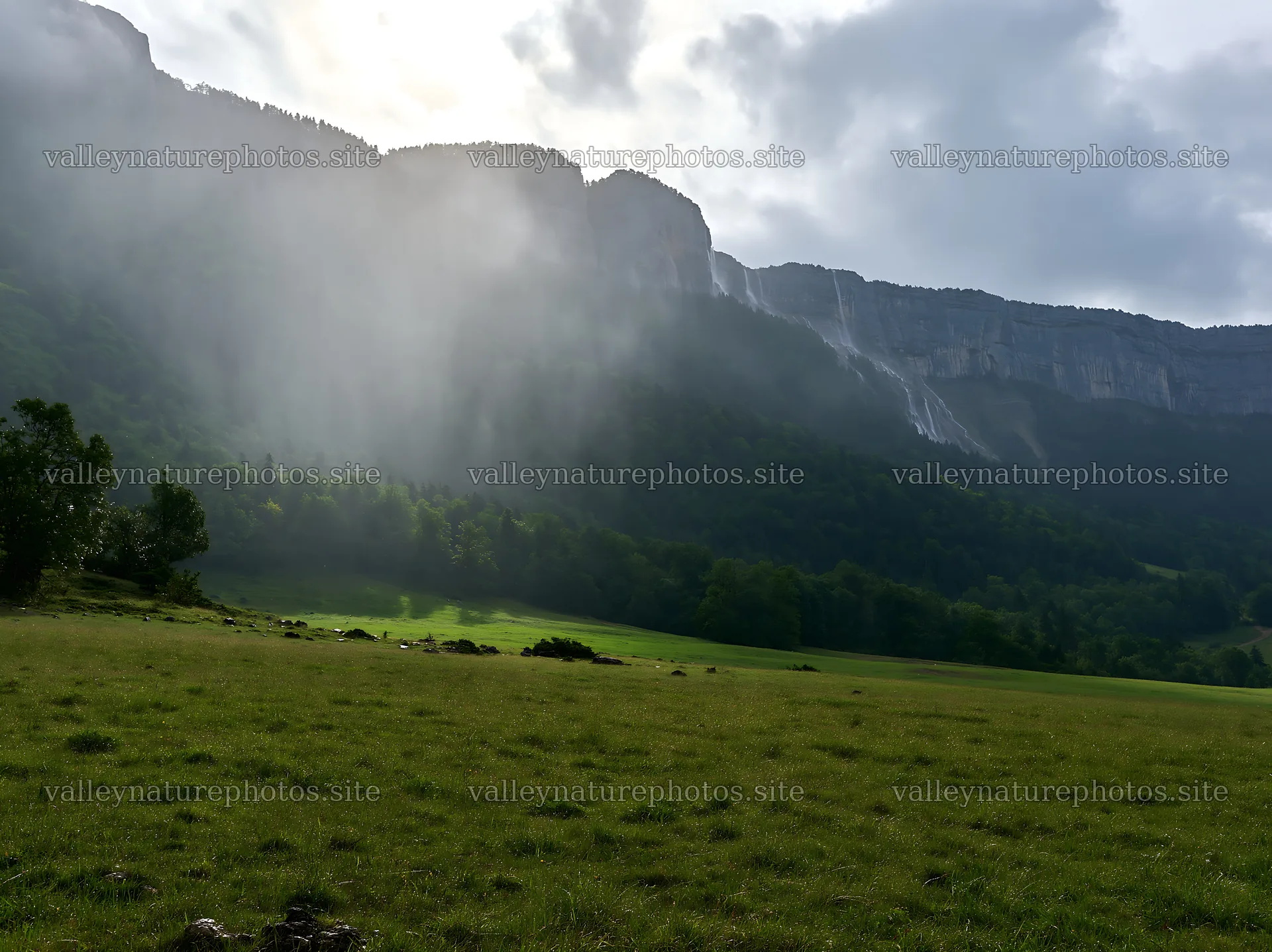 Meadow beneath crags with mist and waterfalls in the distance – nature photography 9174x6866