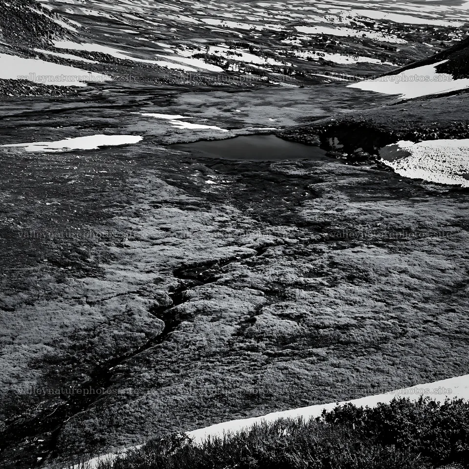 Aerial view of snowy meadow valley with dark water pool – nature photography 7938x7938