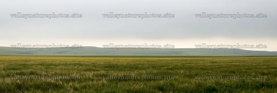 Cloudy limestone meadow with grass and hills in the background – nature photography 13690x4602